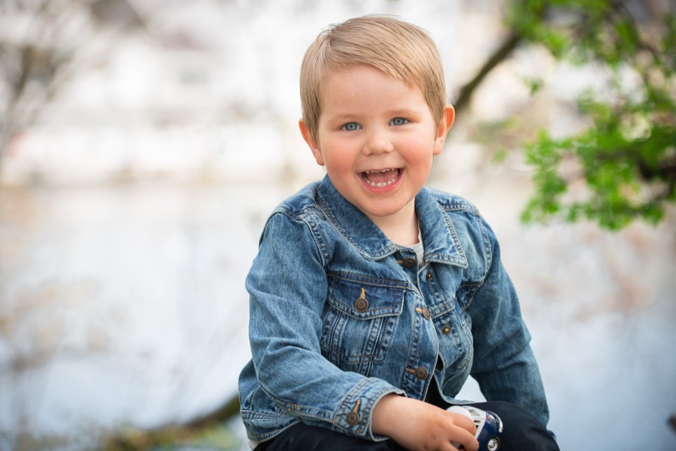 A laughing child in a denim jacket, from a family photo session