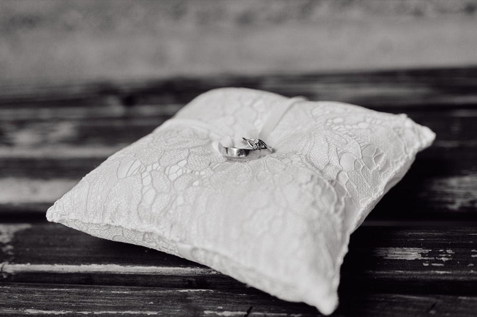 Wedding rings resting on a lace pillow, photographed in black and white