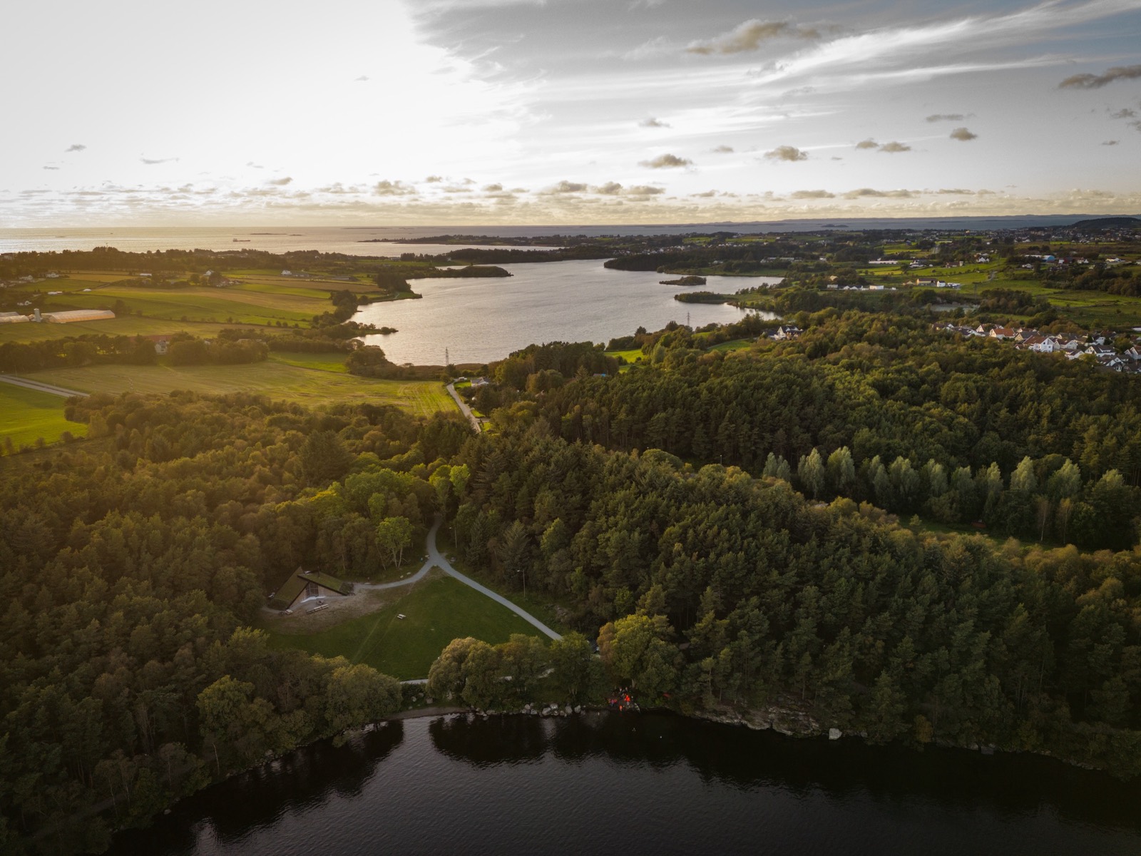 Aerial view of the coast of Western Norway at golden hour, forest and lakes stretching to the sea